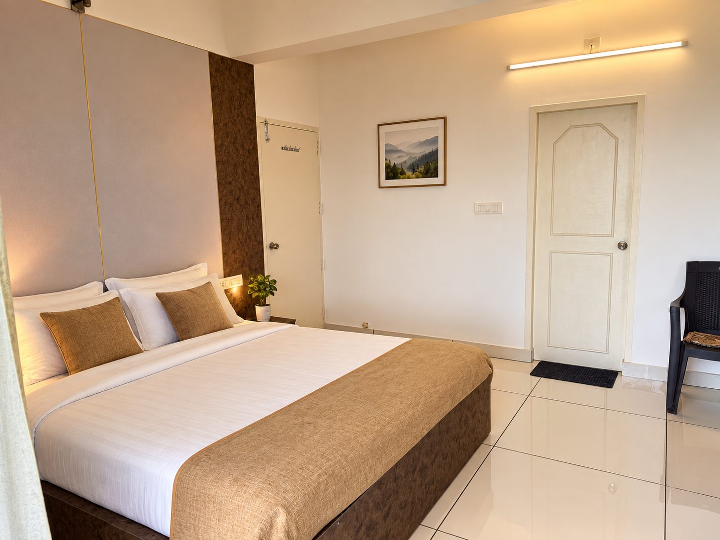 A 2 BHK bedroom with white linens, warm accents and a quiet interior