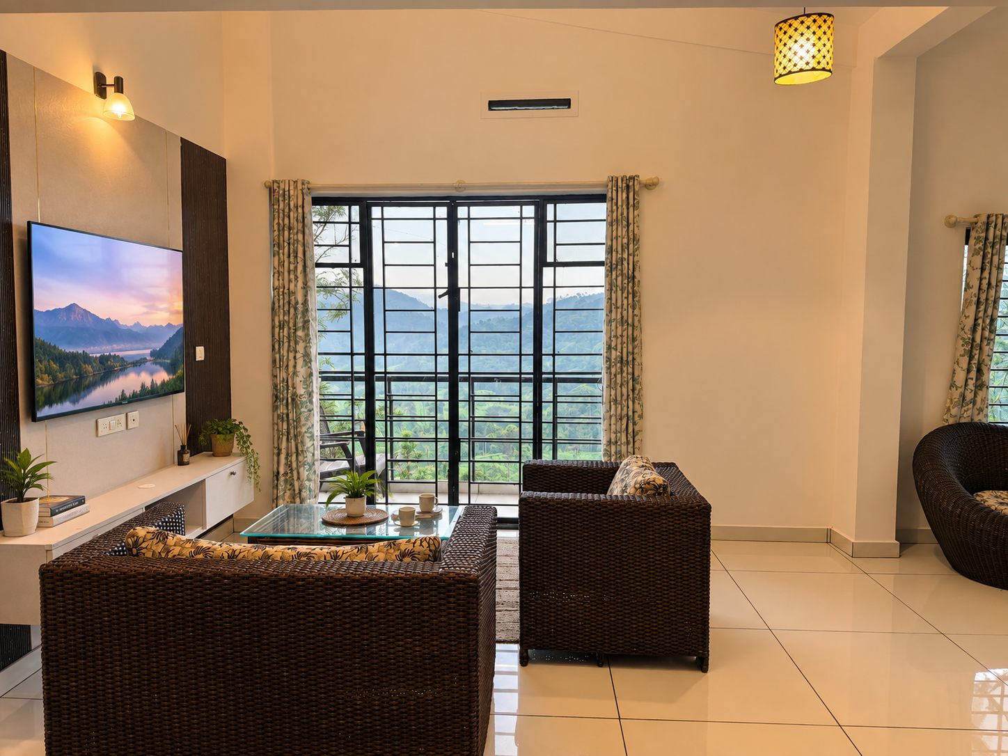 The 2 BHK living room at Green Peaks, with rattan seating and a balcony view to the hills