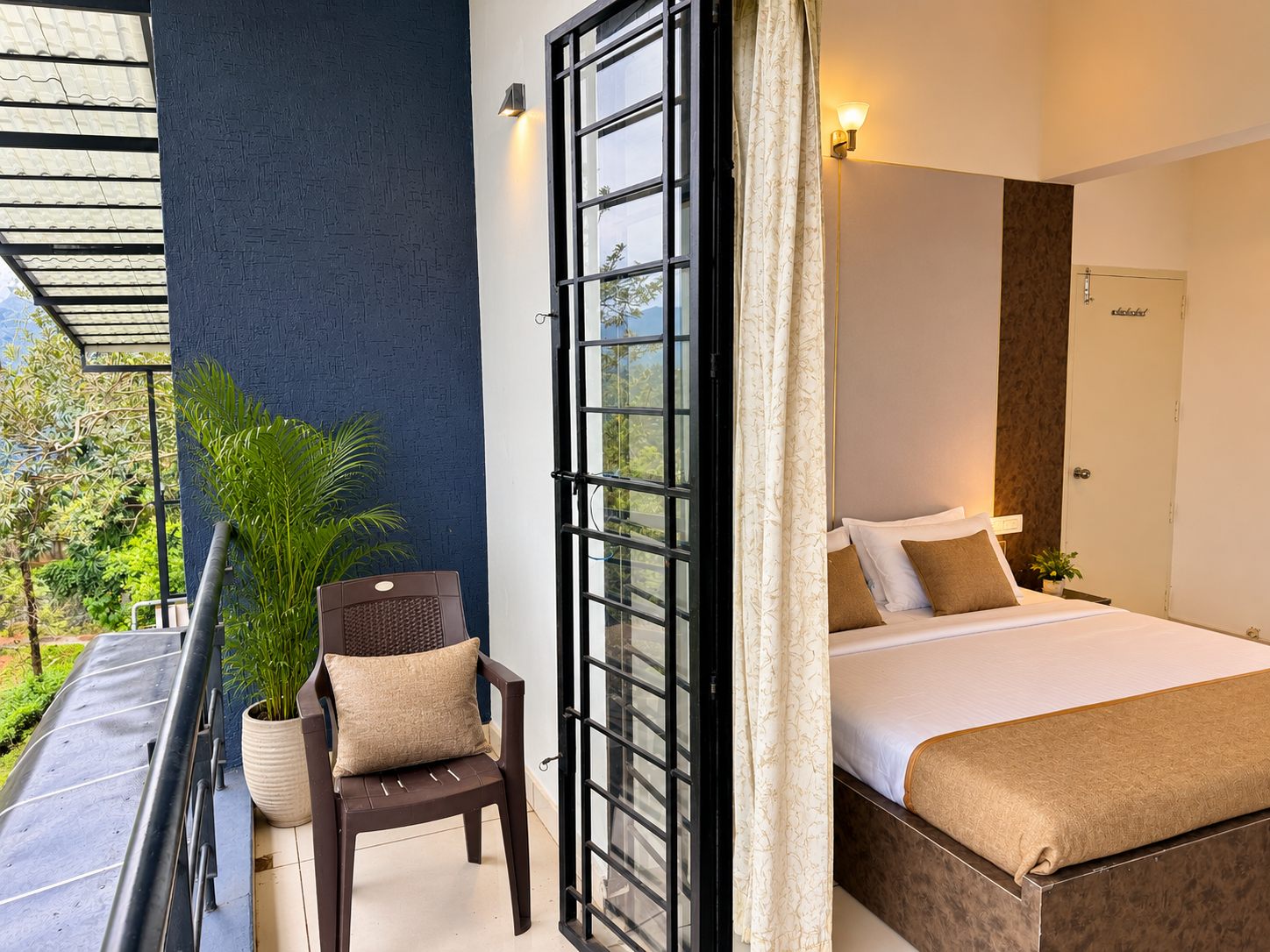 A 2 BHK bedroom opening onto a covered balcony above the forested hillside